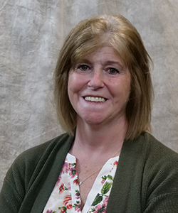 a woman with strawberry blond hair wearing a white print shirt with a green cardigan